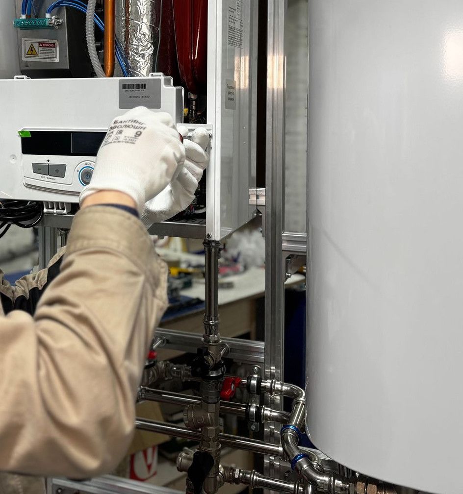 Technician installing or repairing a heating system in an indoor workshop setting.